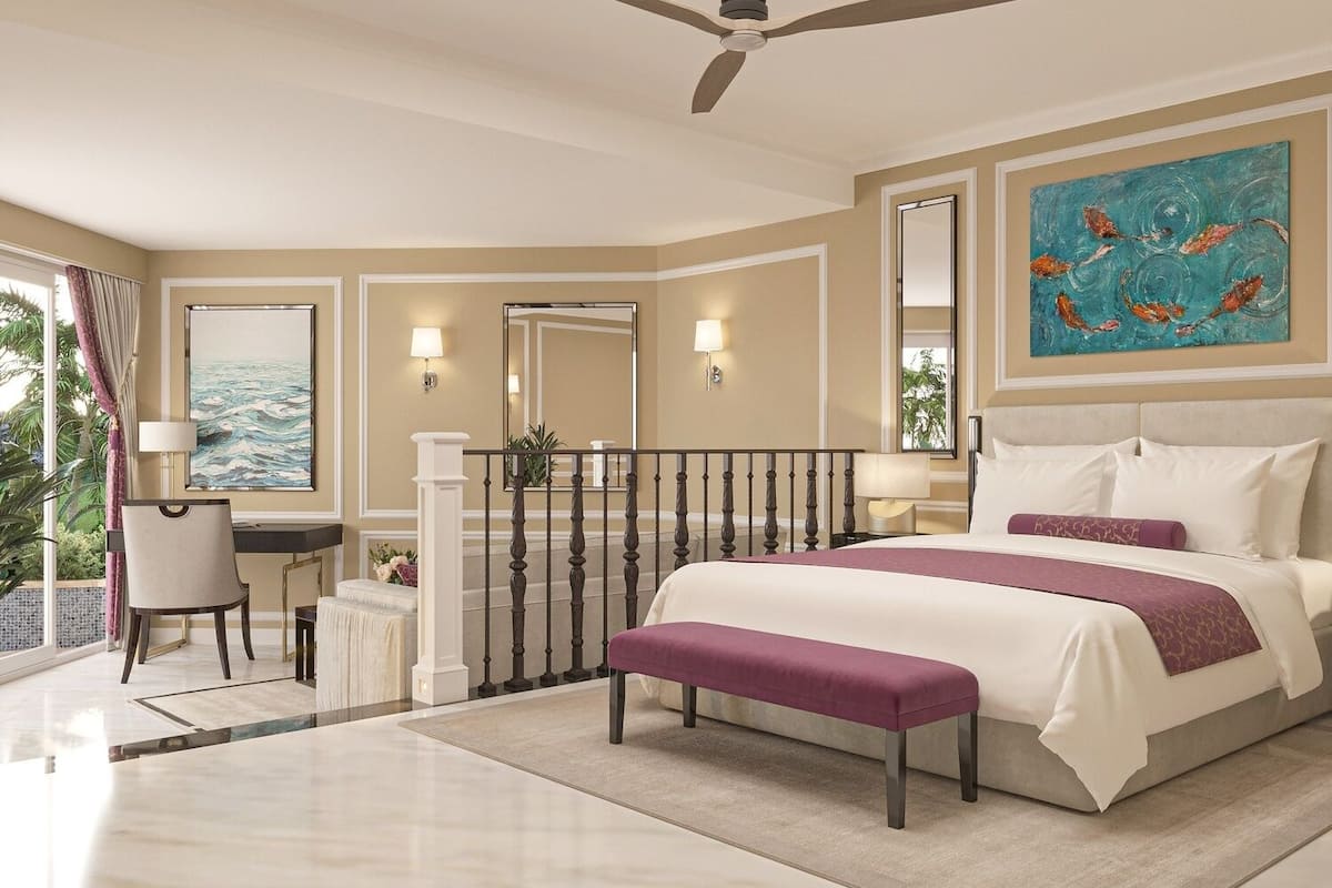 A hotel room with a bed, a desk, a chair, a balcony with a view, and a ceiling fan.