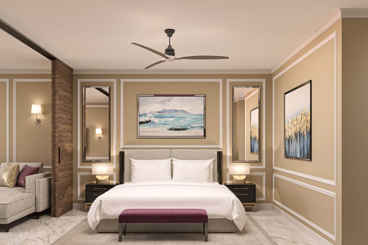 A modern bedroom with a large bed, a ceiling fan, and artwork on the walls.
