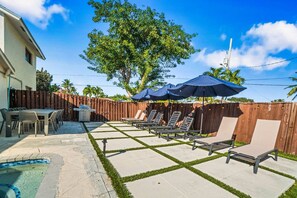A backyard with a pool, patio furniture, and a wooden fence. - Heated Pool - Putting Green - 5 min from Beach! (Deerfield Beach)