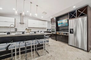 A modern kitchen with a central island, stainless steel appliances, and pendant lighting. - Heated Pool - Putting Green - 5 min from Beach! (Deerfield Beach)