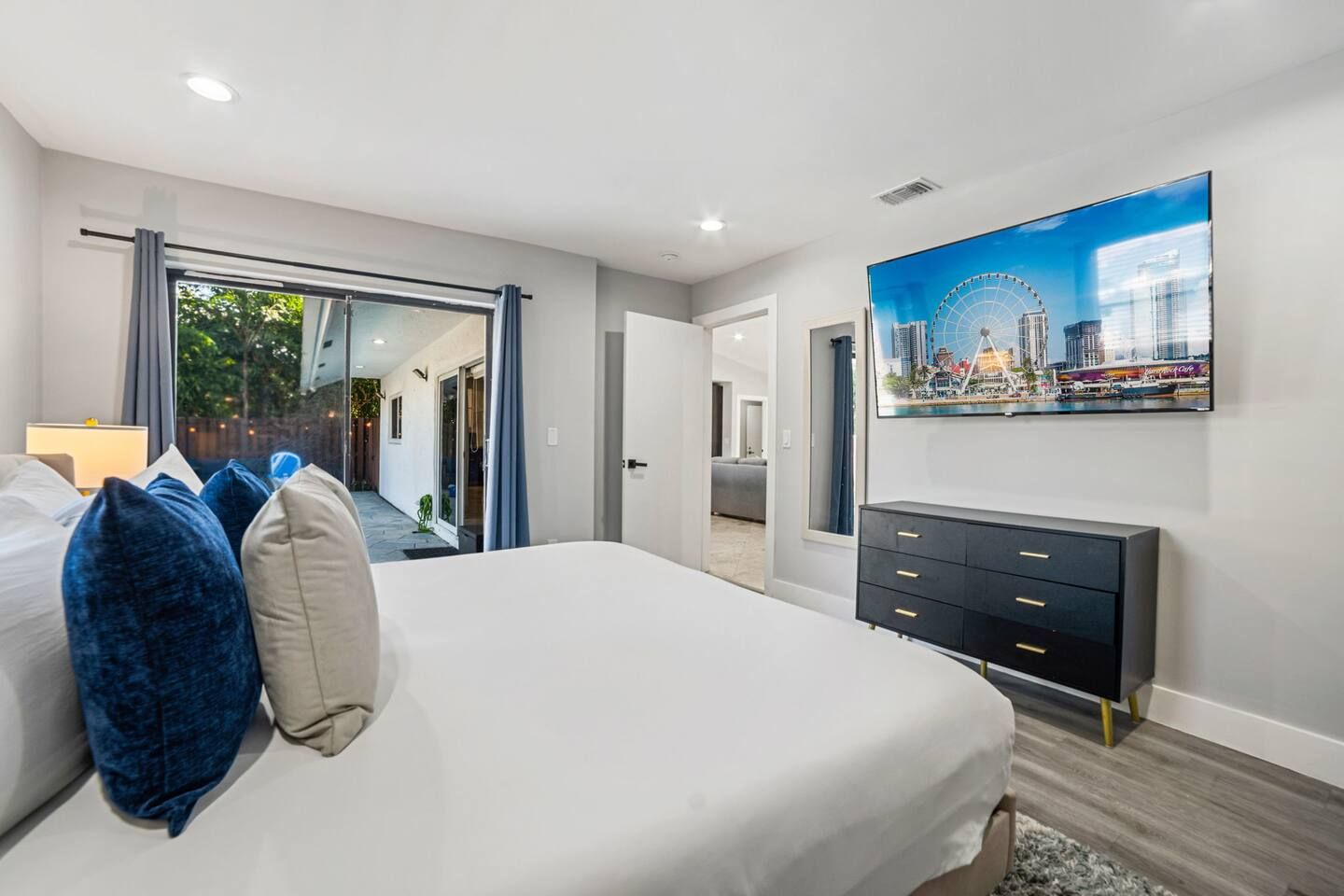 Une chambre d’hôtel avec un lit, une commode, une grande fenêtre et un tableau représentant un paysage urbain.