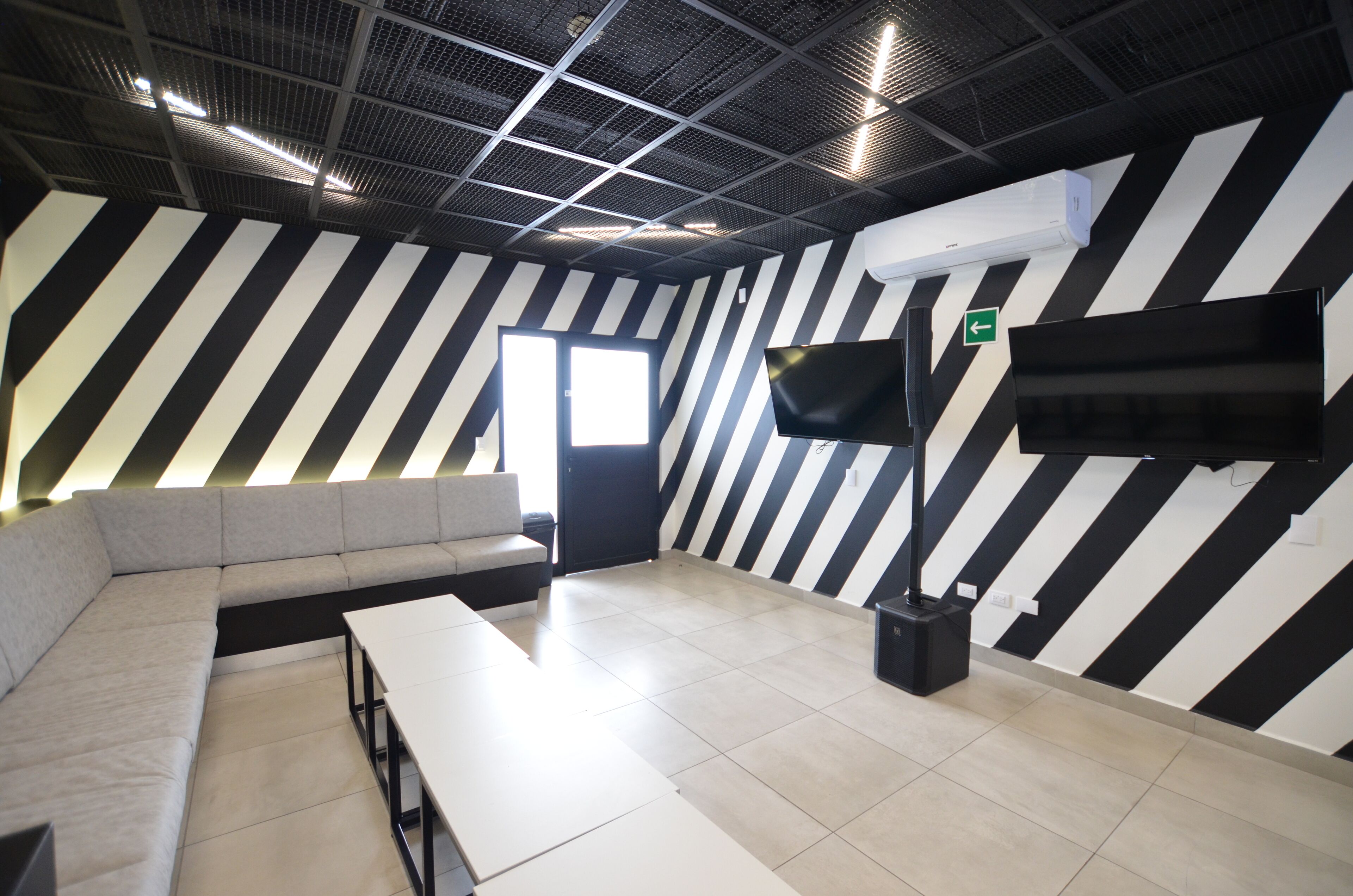 A modern room with a black and white striped wall, a flat-screen TV, a sofa, and a table.