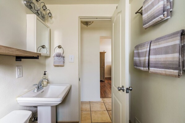 Un baño con un lavabo blanco, un espejo y un toallero.