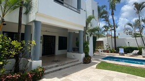 A two-story house with a pool, surrounded by palm trees and a well-maintained lawn. - Fabulous 4-bedroom Home, 900 Meters from Ocean in Cozumel (San Miguel de Cozumel)