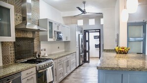 A modern kitchen with a stove, oven, microwave, and refrigerator. There is a ceiling fan and a fruit bowl on the counter. - Fabulous 4-bedroom Home, 900 Meters from Ocean in Cozumel (San Miguel de Cozumel)