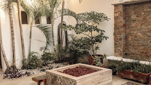 A courtyard with a tiled floor, a wooden bench, a planter box with red soil, and various potted plants. - Fabulous 4-bedroom Home, 900 Meters from Ocean in Cozumel (San Miguel de Cozumel)