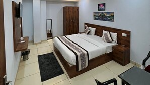 A modern bedroom with a large bed, bedside tables, a wardrobe, and a ceiling fan. - Hotel RK palace near airport (Jaipur)