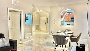 A modern interior with a dining area, a kitchen with wooden cabinets, and a hallway leading to another room.