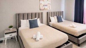 A hotel room with two beds, a ceiling fan, a small bedside table, and a wall-mounted artwork. - 4102-404 Retreat: Balcony, Resort Amenities & MORE (Orlando)