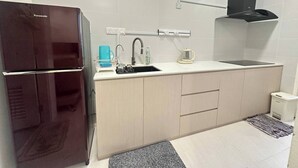 A compact kitchen with a refrigerator, sink, and a range hood. - Cozy Kuching Suite at Riverine Kuching (Kuching)