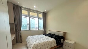 A bedroom with a bed, a nightstand, a wardrobe, and a window with curtains. - Cozy Kuching Suite at Riverine Kuching (Kuching)