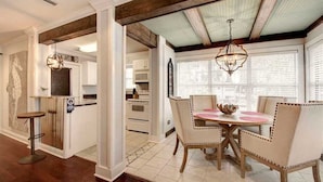 A dining area with a round table and four chairs, a bar stool, and a chandelier. - Island Square condo #808 (Saint Simons Island)