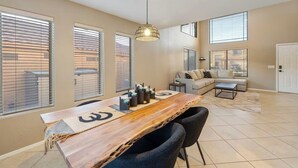 A modern living room with a wooden dining table, black chairs, a sofa, and a hanging light fixture. - Tranquil Retreat in Cave Creek (Cave Creek)