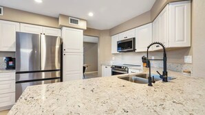 A kitchen with white cabinets, stainless steel appliances, a granite countertop, and a black faucet. - Tranquil Retreat in Cave Creek (Cave Creek)