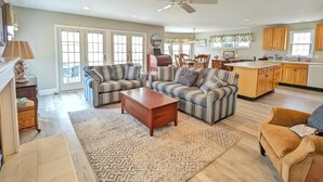 A spacious living room with two striped sofas, a coffee table, and a patterned rug. - Comfortable Southend 4BR Condo • Sleeps 8 • Deck, Parking & Outdoor Shower (Ocean City)