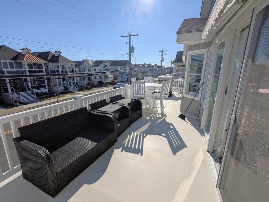 Un balcon avec un canapé en osier, une petite table et une chaise.