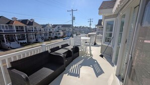 Un balcon avec un canapé en osier, une petite table et une chaise.