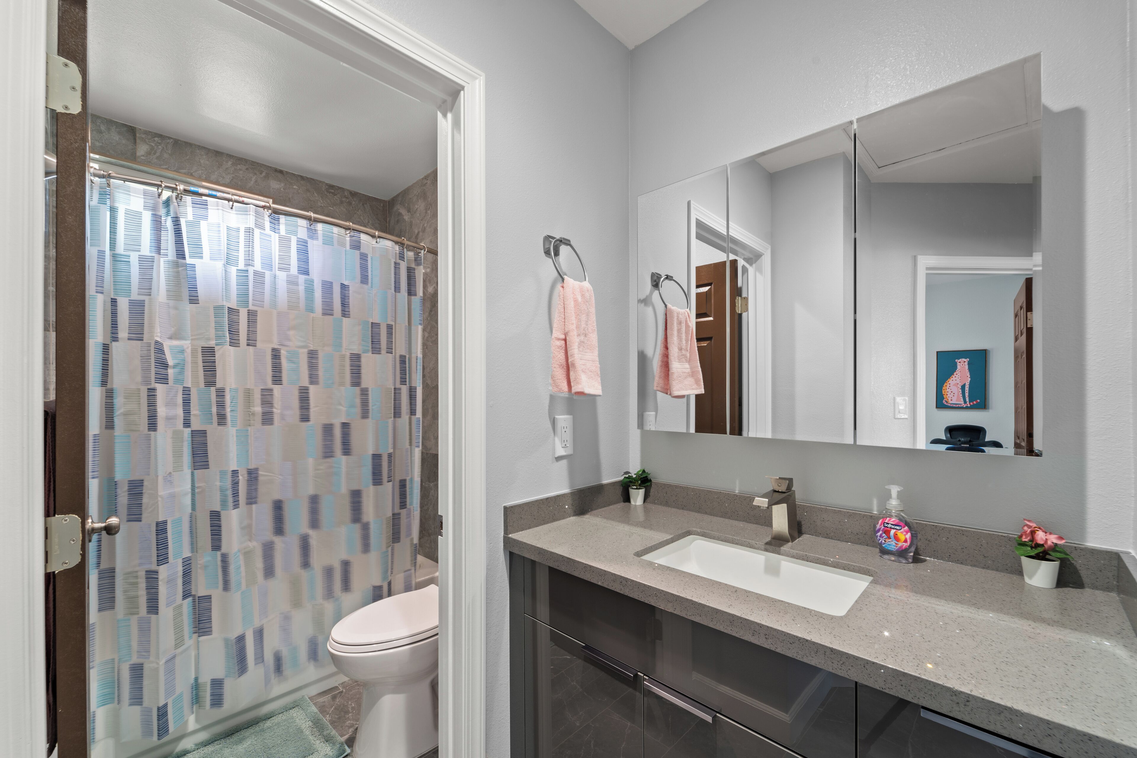 A modern bathroom with a shower, toilet, sink, and large mirror.