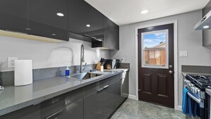 A modern kitchen with dark cabinets, a stainless steel sink, and a built-in stove. - Tranquil 2-bedroom house with AC in pleasant Rosemead (Rosemead)