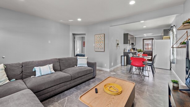 A modern living room with a grey sofa, a wooden coffee table, and a dining area with red chairs. - Tranquil 2-bedroom house with AC in pleasant Rosemead (Rosemead)
