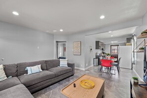 A modern living room with a grey sofa, a wooden coffee table, and a dining area with red chairs. - Tranquil 2-bedroom house with AC in pleasant Rosemead (Rosemead)