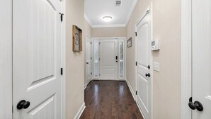 A hallway with white doors, a wooden floor, and a ceiling light. - Close to Island Amenities (St. Simons Island)