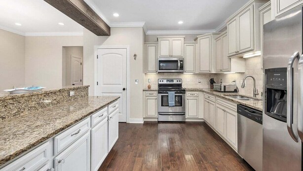 A modern kitchen with white cabinets, granite countertops, stainless steel appliances, and a wooden floor. - Close to Island Amenities (St. Simons Island)