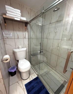 A modern bathroom with a toilet, a glass shower enclosure, and a marble-tiled floor. - 10 on The Ridge, Pet Friendly, (Pigeon Forge)
