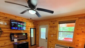 A cozy room with a bed, a ceiling fan, a TV, and wooden walls. - 10 on The Ridge, Pet Friendly, Near Gatlinburg (Pigeon Forge)