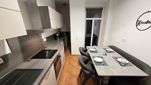 A modern kitchen with a built-in stove, oven, and a dining area with a table set for two. - Executive apartment + terrace + private parking space (Chemnitz)