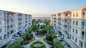 Ein mehrstöckiges Hotel mit Balkonen, einem zentralen Innenhof mit Springbrunnen und Blick auf den Strand.