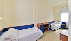 A hotel room with two single beds, a desk, a chair, and a small table. - Villa Elprado (Cervia)