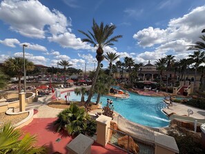 A resort with a large pool, palm trees, and a view of the surrounding buildings. - 4B/3B townhome close to Disney! Onsite pools, hot tubs, gym & restaurant! (Davenport)