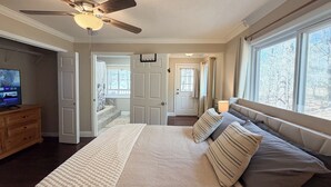 A bedroom with a bed, a ceiling fan, a TV, and a window with a view of trees. - Big Water Views, Private Dock, 7 Kayaks, Sleeps 12 (Sparta)