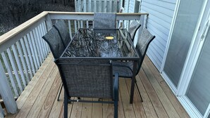 Eine Terrasse mit Tisch und Stühlen, umgeben von einer Holzbrüstung.