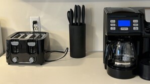 Eine Küche mit Toaster, Kaffeemaschine und einer Utensilienablage auf der Arbeitsfläche.