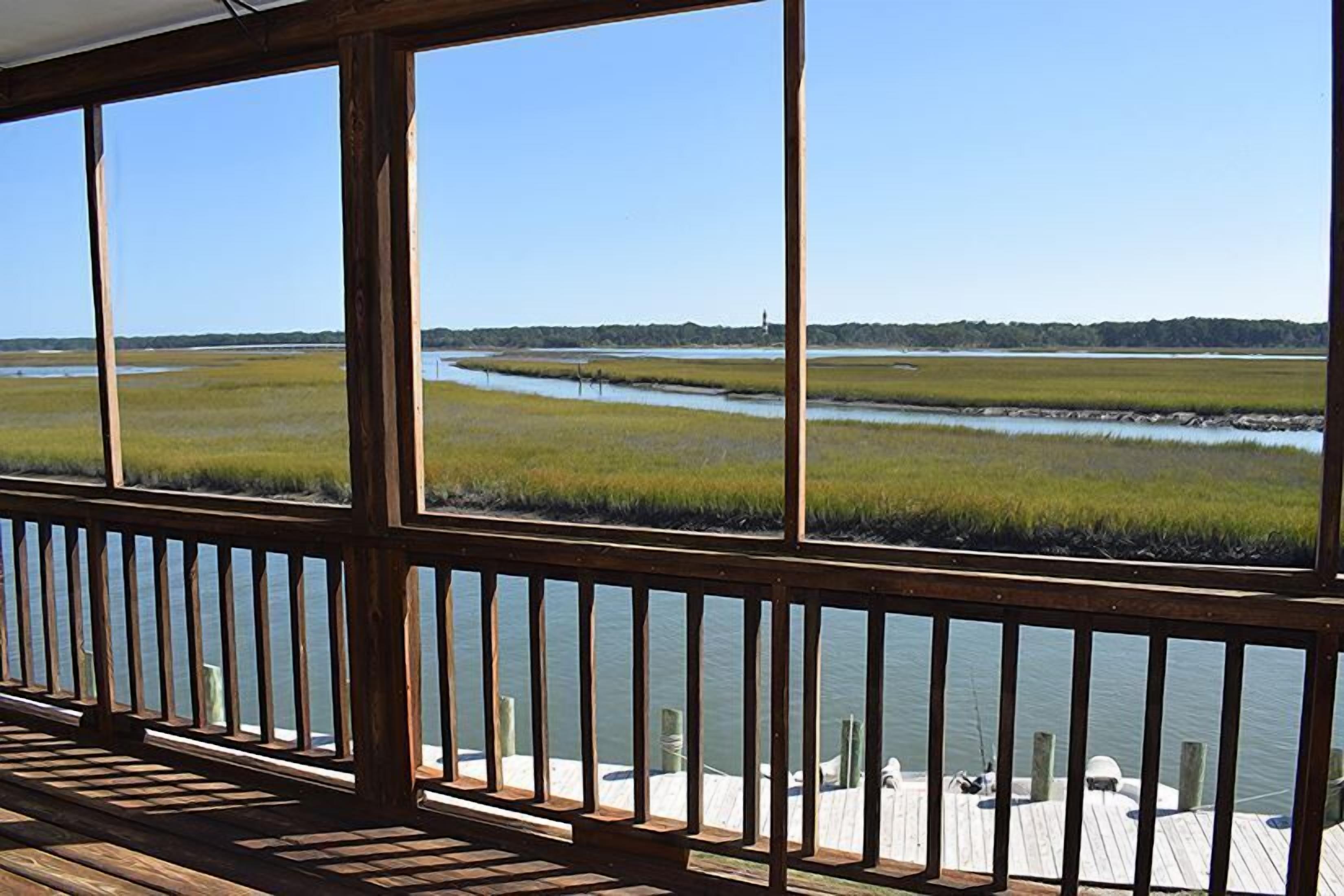 Une terrasse en bois offrant une vue sur un paysage marécageux et un plan d’eau.