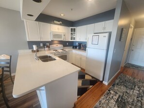 A kitchen with white cabinets, a white island with a sink, a stove, and a refrigerator.