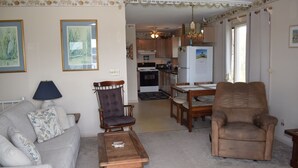 Ein Wohnzimmer mit Sofa, Sesseln, Couchtisch und einem Essbereich mit Tisch und Stühlen.
