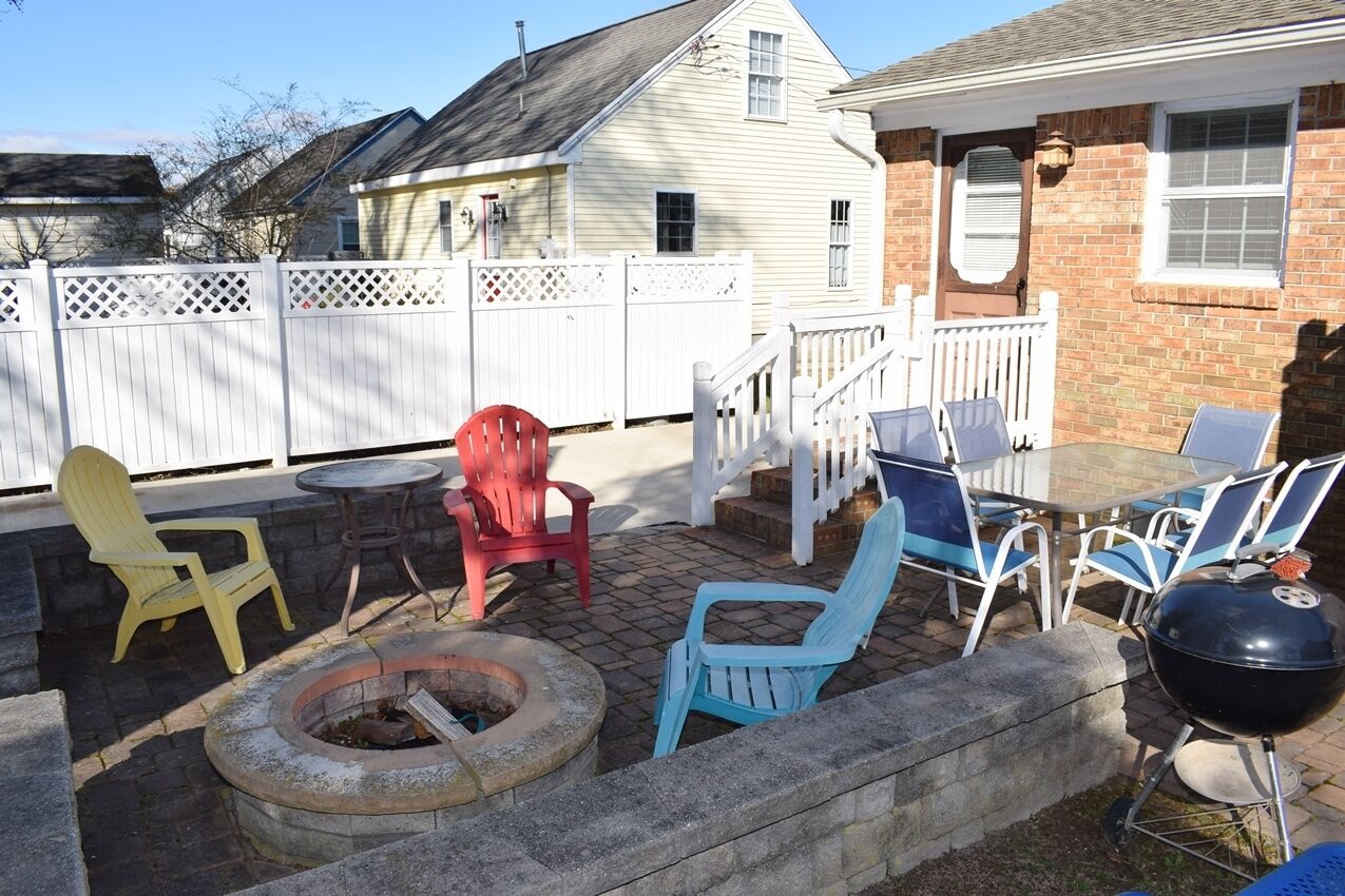 A backyard patio with a fire pit, outdoor furniture, and a grill.
