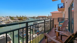 Ein Balkon mit Blick auf einen Yachthafen, Holzstühle und ein Geländer.