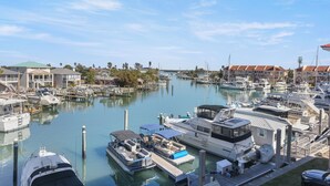 Ein Yachthafen mit verschiedenen Booten, darunter eine festgemachte Yacht, und Gebäuden im Hintergrund.