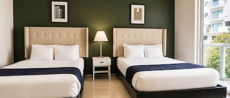 Une chambre d’hôtel avec deux lits, une table de chevet avec une lampe et des œuvres d’art accrochées aux murs.