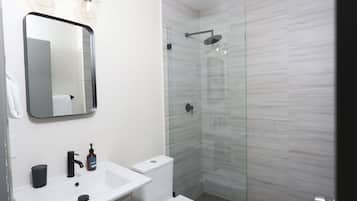 Un baño moderno con lavamanos blanco, grifo negro y cabina de ducha de vidrio.