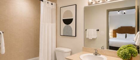 Ein modernes Badezimmer mit einer Badewanne, Toilette, Waschbecken und einem großen, beleuchteten Spiegel.