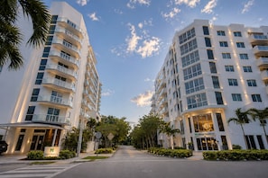 A modern hotel with multiple floors, balconies, and a well-maintained garden area.