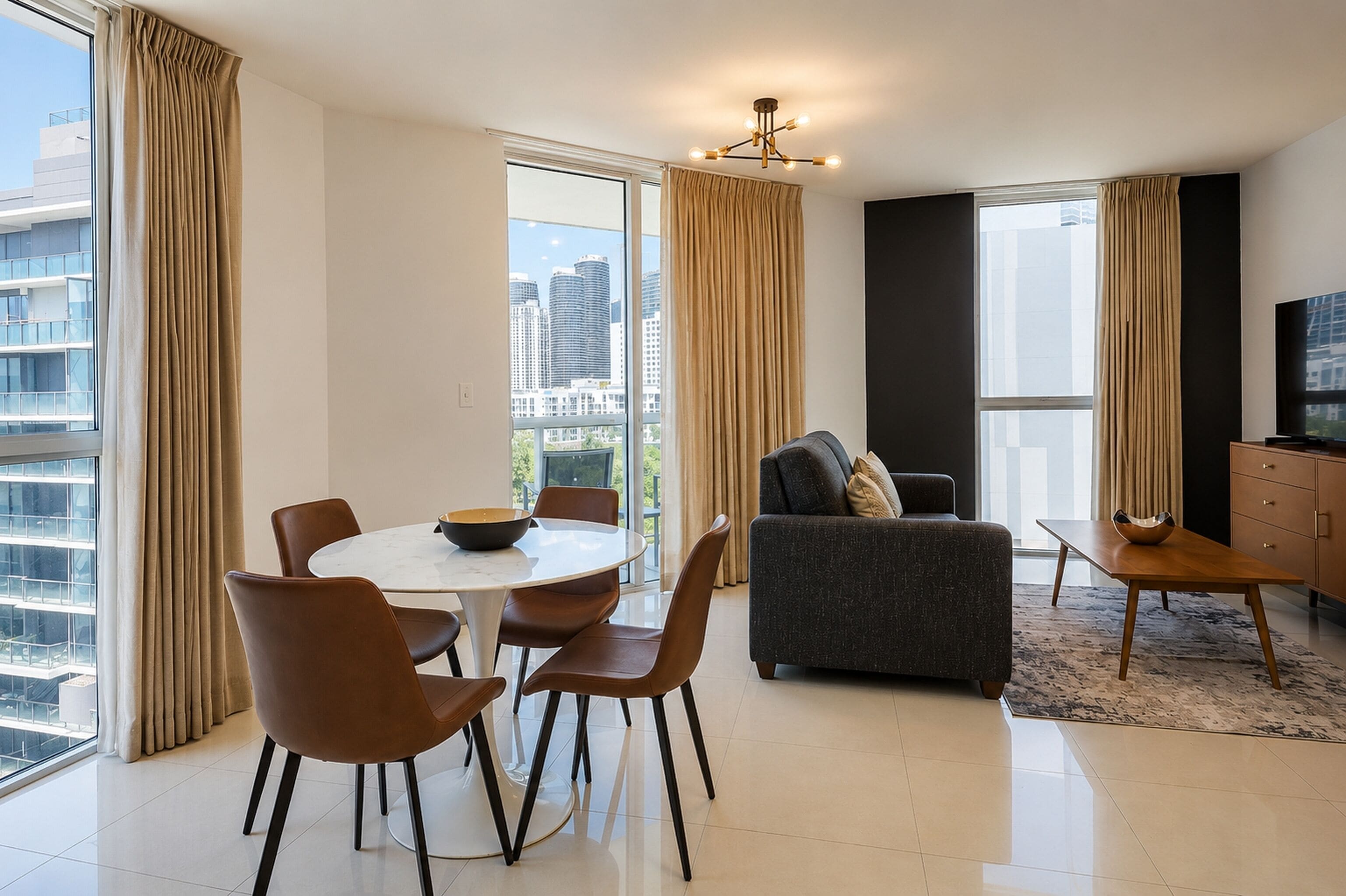 Un salon moderne avec un coin repas, de grandes fenêtres et une vue sur la ville.