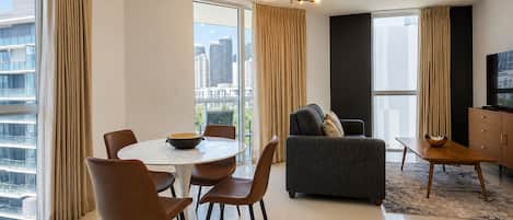 Un salon moderne avec un coin repas, de grandes fenêtres et une vue sur la ville.