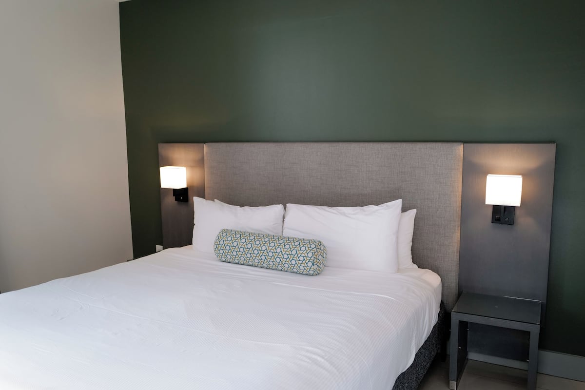 A hotel room with a large bed, two bedside lamps, and a headboard.