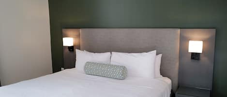 Hotellihuone, jossa on suuri sänky, kaksi yöpöytävalaisinta ja sängynpääty.
